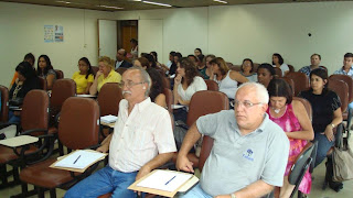 Apanhado geral do auditório todo ocupado pelos participantes e  por outro ângulo, com destaque na primeira fila,  da esquerda para a direita, dos conselheiros Carlos Sachetto (Associação de Surdos de Minas Gerais) e Daniel Antônio Passos (Feneis).