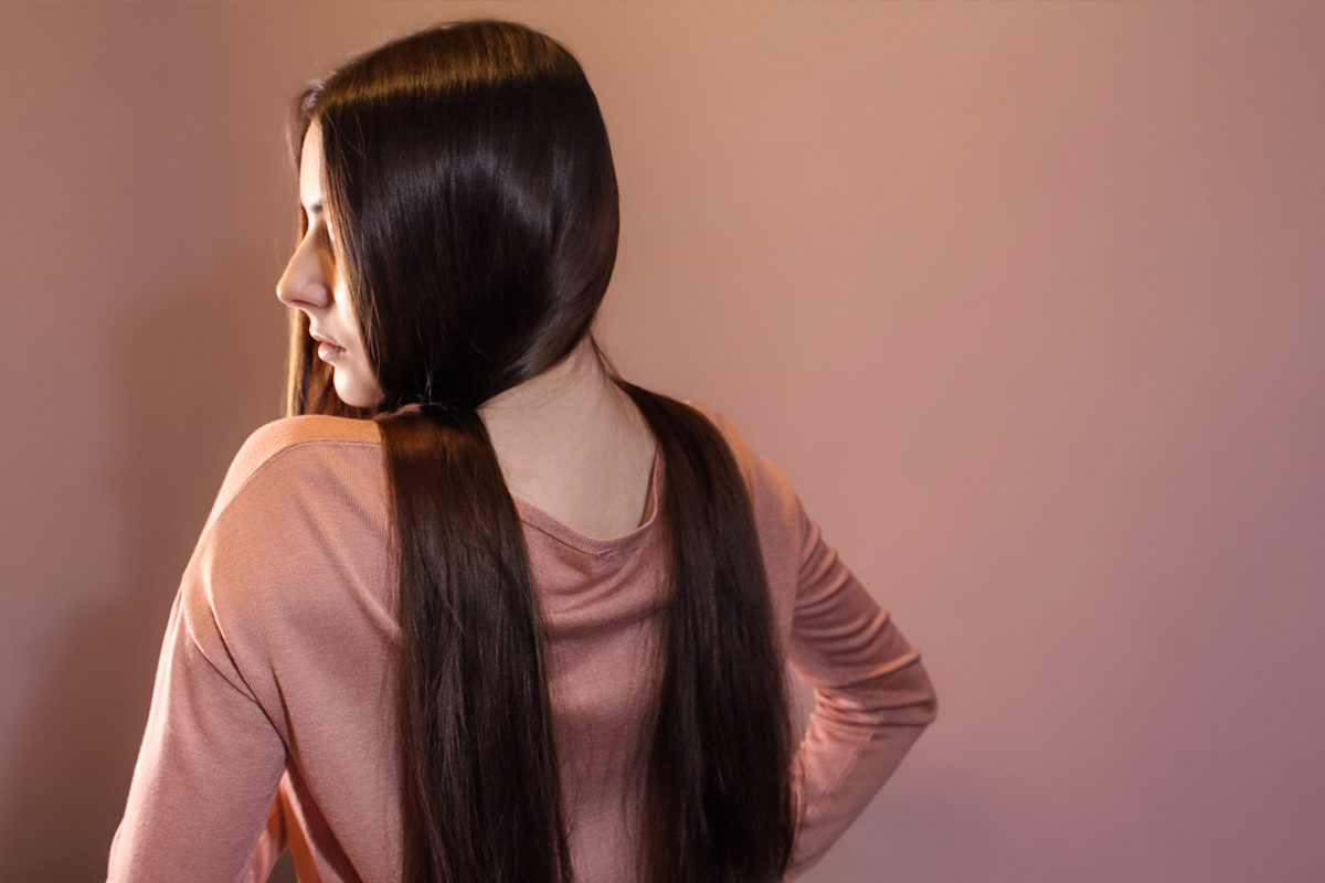woman from the back with long , brown hair laing on her shoulders