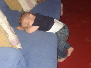 Baby Boy asleep standing up at the edge of the sofa