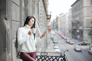 Mujer en un balcón, revisando sus redes sociales.