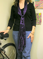 Purple scarf draped around neck then tied in front.