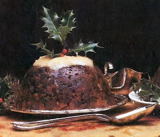 Traditional steamed rich christmas pudding topped with white sauce and a sprig of holly