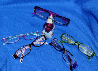 five pairs of reader glasses and a nose eyeglass holder