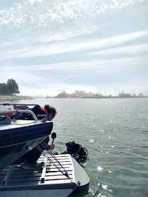 Haastattelija mikrofonin kanssa veneessä, sukeltaja vedessä. 