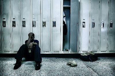 Teenager sitting on the floor beside his opened locker