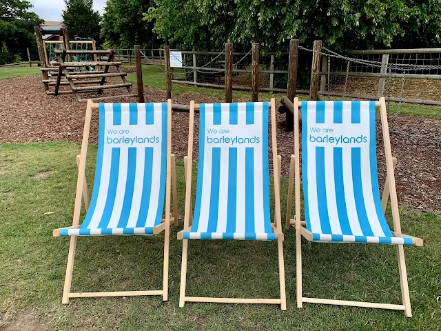 3 deckchairs saying "we are barleylands" and a play area in the background