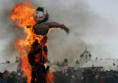 scarecrow burning in frontt of a large crowd