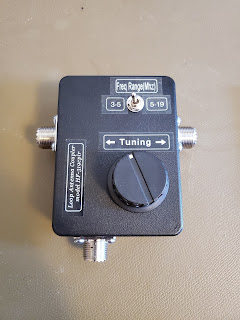 Front view of the HF-319 tuning box with UHF connectors on each side and the top. The product label says "Loop Antenna Coupler model HF-319cplr". The upper switch is labeled "Freq Range (MHz)" with positions "3-5" and "5-19". The lower knob is labeled "Tuning" with left and right arrows.