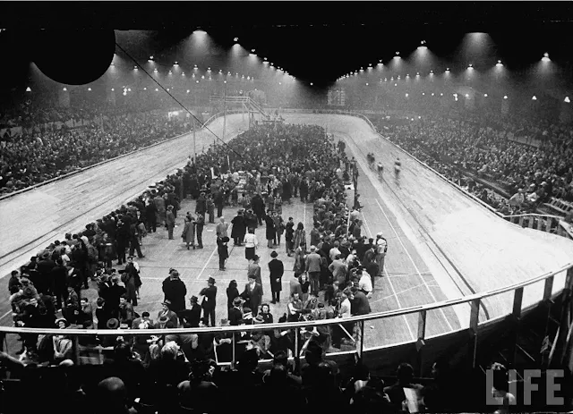 Imagem em preto e branco de pessoas aglomeradas nas arquibancadas e no centro do velódromo