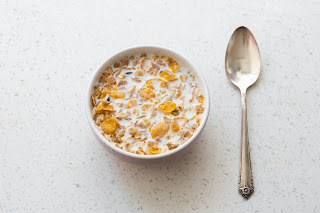 a bowl of cereal and milk with a spoon next to it