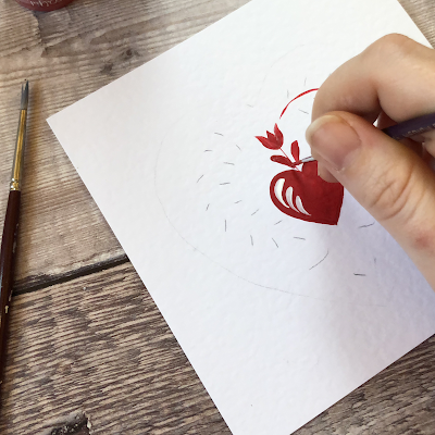 Red heart and folk art tulip being painted on to a white greetings card