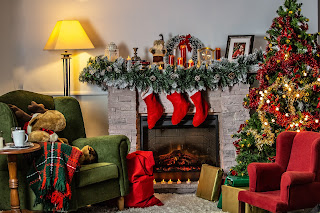 Christmas tree beside a cozy fireplace with stockings and decorations hung up