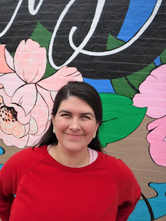 a woman with dark hair stands in front of the Sioux City mural by Jenna Brownlee