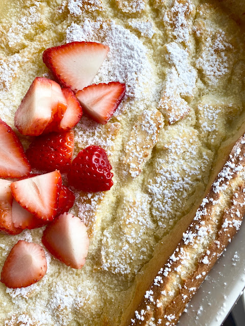 Overhead view of Swedish Oven Pancake topped with powdered sugar and sliced strawberries.