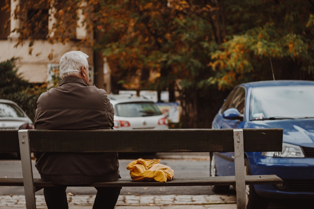 An elderly man suffering from Parkinson’s sitting on a bench