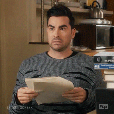 Gif of David from Schitt's Creek holding a stack of papers and looking back and forth with a concerned expression