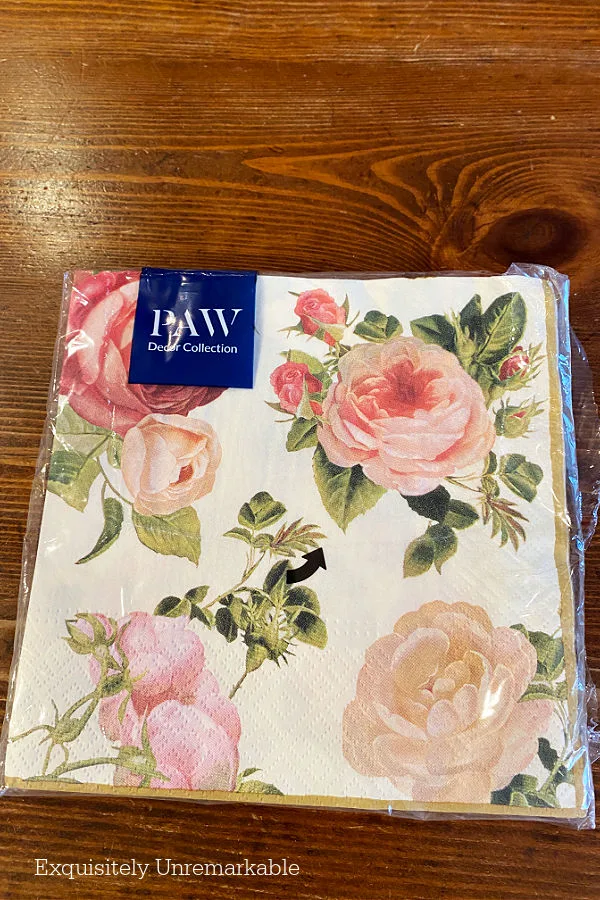 Package of pink and red rose covered paper napkins on a table