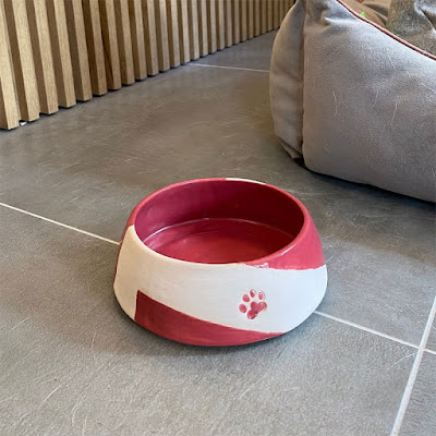 Ceramic pet bowl in red and white with a red paw print