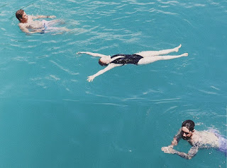 Image of three swimmers. One kicking backwards, one floating and one doing breaststroke. Lean To swim.