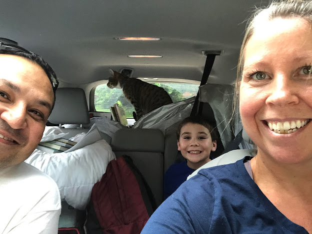 Family in car with cat in the back looking out window