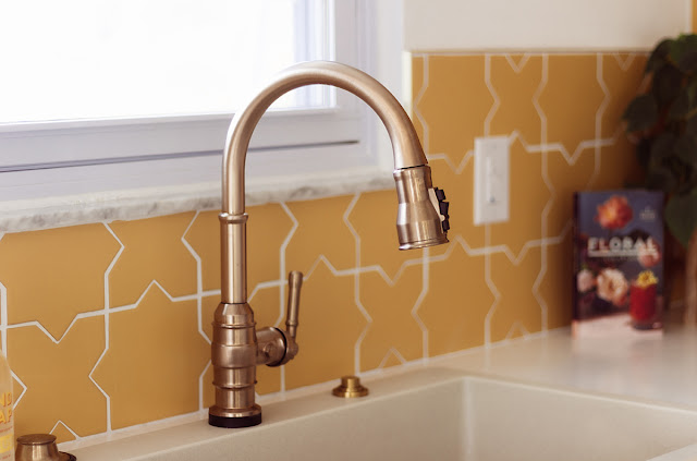 Close up of the kitchen sink with sun yellow tile backsplash behind.