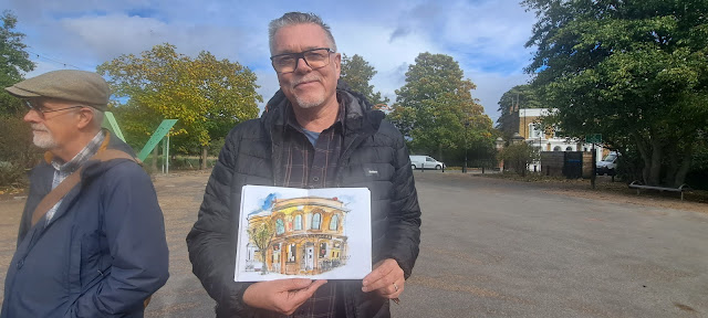 An artist hold up his watercolour painting of the Lord Tredegar Public House.