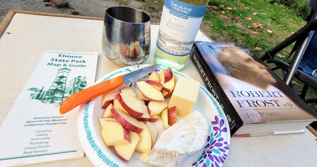 Plate of apple, cheese and crackers, bottle of wine, and Robert Frost book.