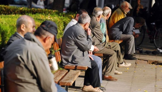 Some old men sitting on the benches of a flower garden in Athens