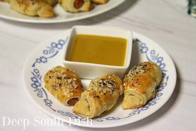 Cocktail smoked sausages, wrapped in puff pastry and topped with fresh Parmesan with bagel seasoning and black pepper and served with a homemade mustard sauce.