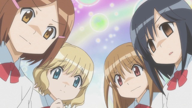 The main four girls up-close hovering over something and each looking concerned