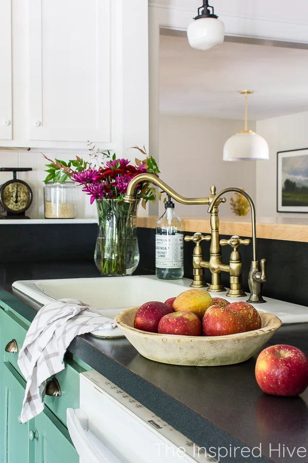 Farmhouse kitchen sink with fall florals and bowl of red apples on the counter