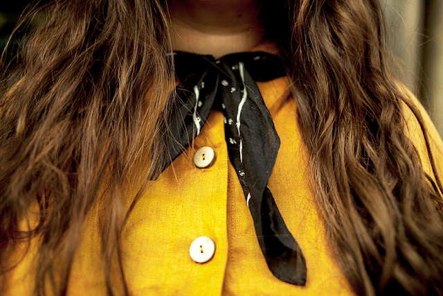 An outfit consisting of a black wide brim hat, an ochre linen baby doll dress, brown tote bag and brown d'oray flats.