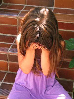 NAMC montessori crying in the classroom girl on steps holding face