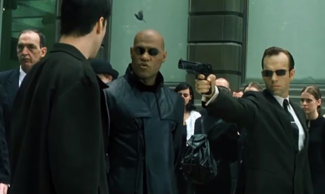 Agent Smith pointing a gun at Neo and Morpheus in the training program