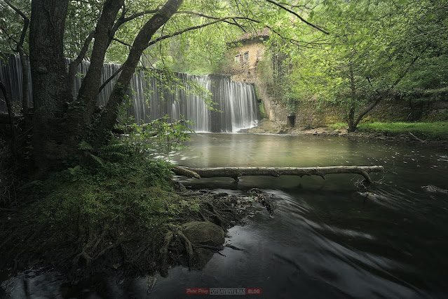 cauce de un río que nos conduce a la cascada de una presa y el viejo edificio de un milino hidraulico