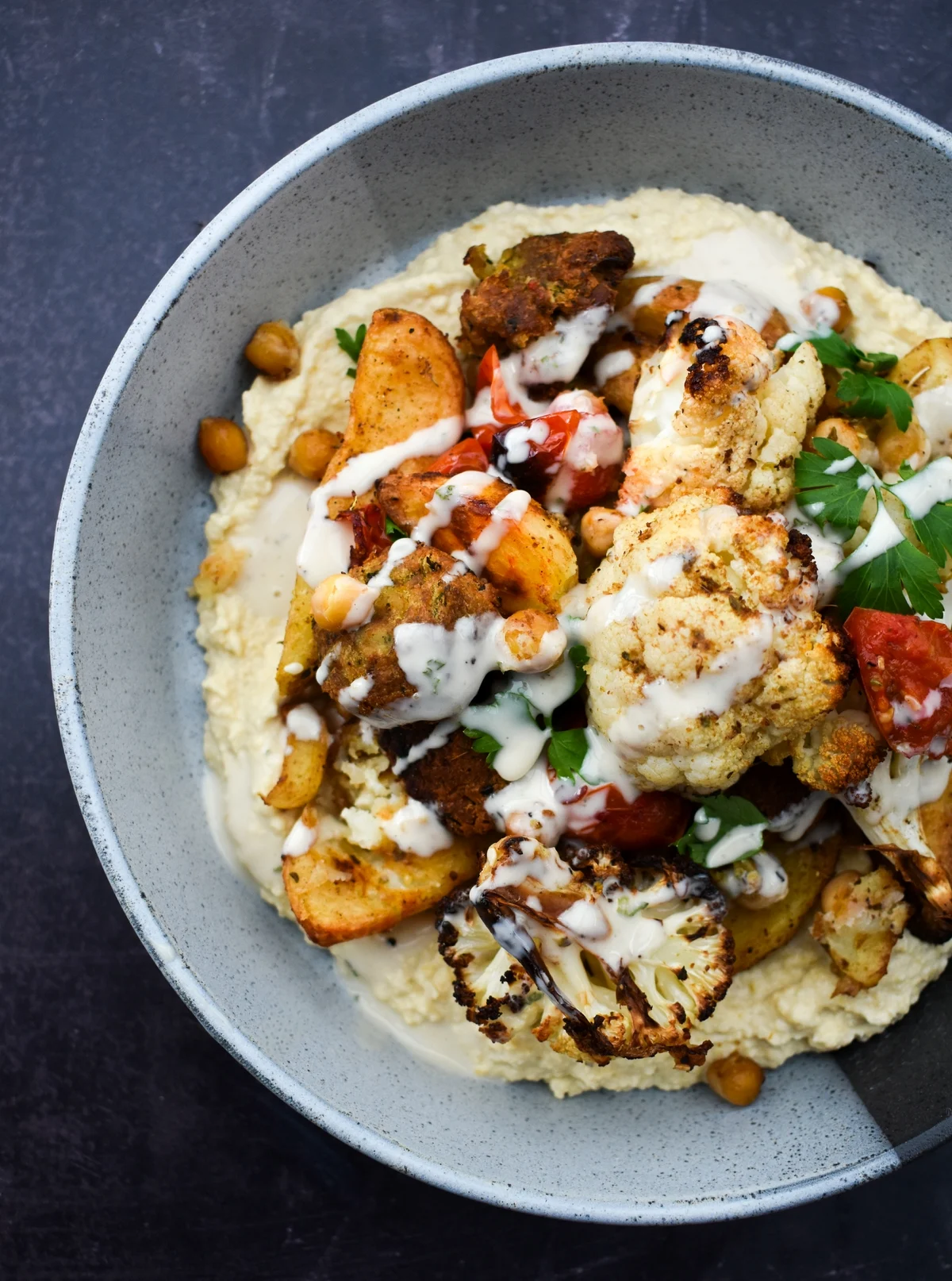 Close up of cauliflower potato bake on a bed of creamy hummus.