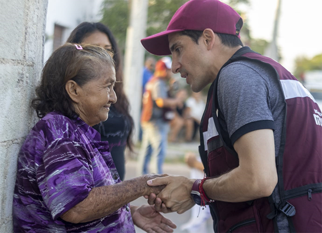 Rommel Pacheco, candidato de Morena a la alcaldía de Mérida, platica con vecinas a las puertas de una casa