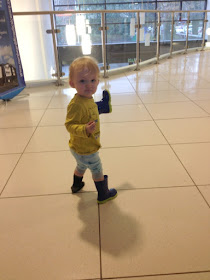 toddler holding one wellie and wearing the other