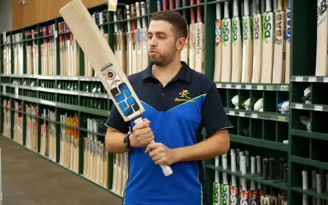 A man in smart clothing stands with a premium cricket bat in hand, showcasing his readiness for the game ahead.