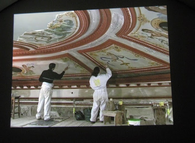 Um homem e uma mulher retocando as pinturas do teto do Palácio do Freixo