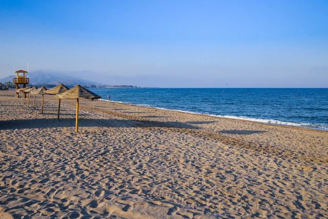 Playa de arena fina con sombrillas y las azules aguas del mar a su frente