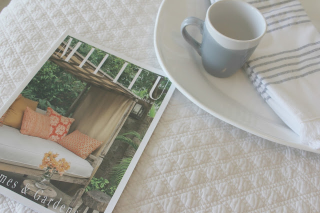 Milieu magazine on quilted coverlet in cozy serene bedroom by Hello Lovely Studio