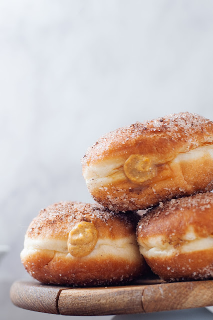 stack of three donuts on a wooden stand.