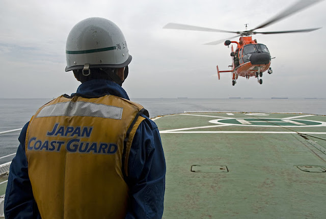 Cover Image Attribute: A file photo of a crewman aboard the Japanese Coast Guard Cutter Mizuho, prepares an HH-65 Dolphin helicopter, from Air Station Barbers Point, Hawaii, to landing on the Mizuho. Source: Coast Guard photo by Petty Officer Jonathan R. Cilley, Nagoya, 16 October 2007, Wikimedia Commons