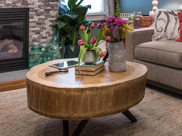 a dark brown wood tree stump coffee table with two hand made vases on top