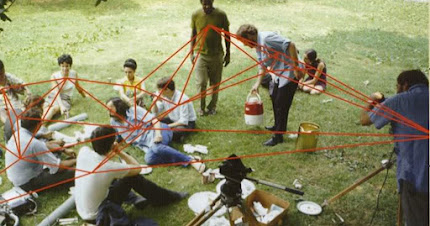 Several individuals sitting in a park. There are red lines superimposed connecting them all.