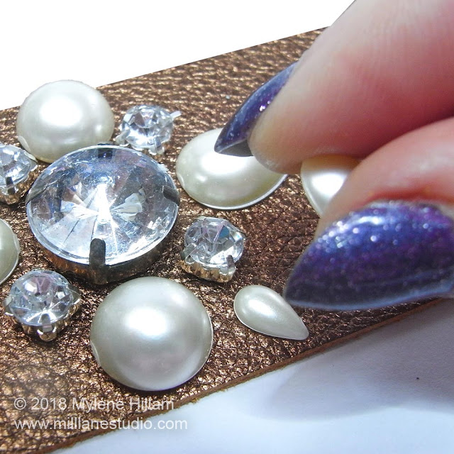 Attaching the pearls and rhinestones to the cuff with adhesive.