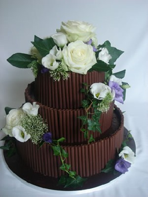 Four tier wedding cake decorated with chocolate cigarillos and fresh bright