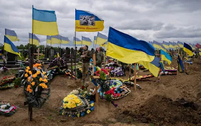 Dois soldados da guarda nacional bebem uma dose para homenagear a memória de dois soldados falecidos no cemitério de Kharkiv, leste da Ucrânia, em 22 de maio de 2022. (AP Photo/Bernat Armangue)