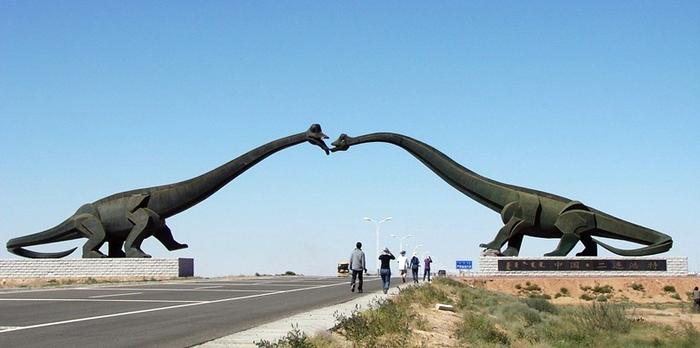 North of China on the Sino-Mongolian border, near the town of Erenhot (also known as Erlian), you will find the statues of two towering Brontosauruses. The two dinosaurs are located on either side of the main highway, their long necks stretching to the other, until the two dinosaur's mouth meet as if to share a kiss. Each dinosaur statue is 34 meters wide and 19 meters high. The span of the two together reaches 80 meters. The ground near the kissing couple is littered with many dozen smaller statues of dinosaurs of all shapes and sizes.